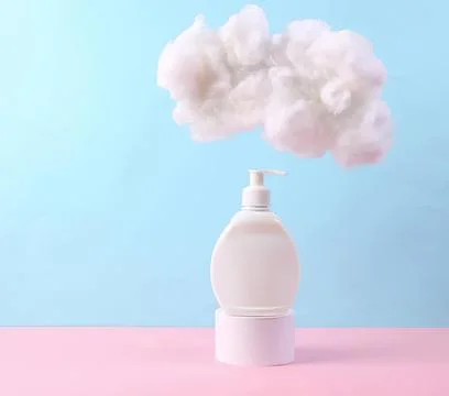 White pump bottle with pink cloud of cotton on pastel background 스톡 사진