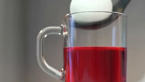 White pure egg is added to a mug of food coloring. Decoration of chicken eggs Stock Footage 128758468