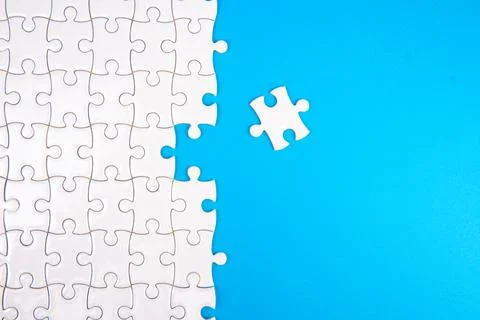 White puzzle with one missing piece on bright blue background. Stock Photos