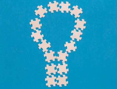 White puzzles in the shape of a light bulb on a blue background, flat lay. Foto stock