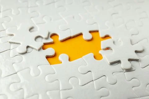 White puzzles without two puzzles on orange background Stock Photos