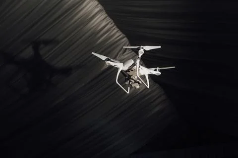 White quadrocopter fly inside the party-tent . Dark background, club light and Stock Photos