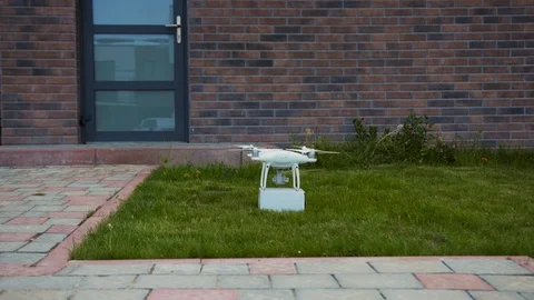 White quadrocopter with parcel standing and flying away. View of innovation 動画素材 113799192