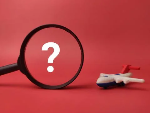 A white question mark inside a black magnifying glass faces a miniature toy.. Stock Photos
