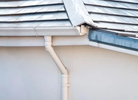 White rain gutter and pipe at the corner of the roof. Stock-Fotos