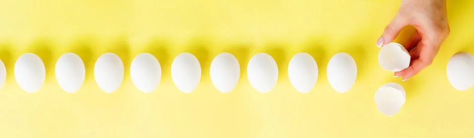 White raw chicken eggs lying in row on a yellow trendy background and female  Stock Photos