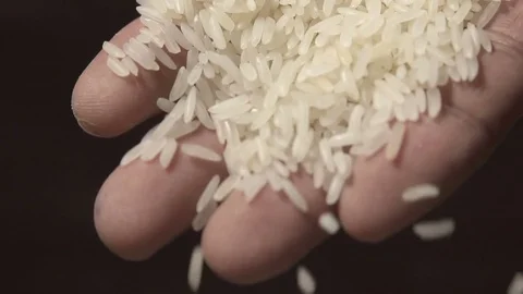 White raw rice grains are falling from a man's hand in slow motion 库存影片 79614007