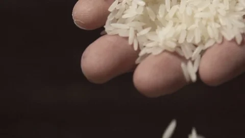 White raw rice grains are falling from a man's hand in slow motion Video stock 79617611