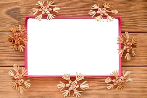 The white rectangle is surrounded by straw snowflakes. Warm wood background Stock Photos