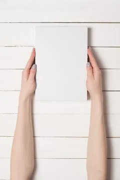 White rectangular box in female hands. Top view. White table on the backgroun 스톡 사진