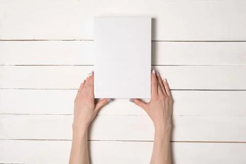 White rectangular box in female hands. Top view. White table on the backgroun 写真素材