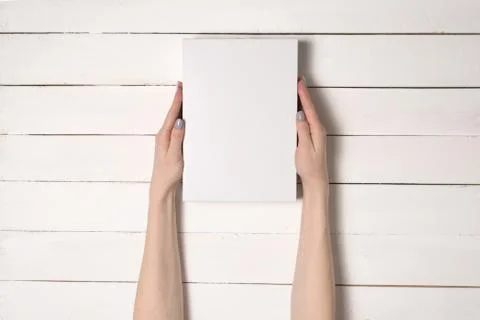 White rectangular box in female hands. Top view. White table on the backgroun 스톡 사진
