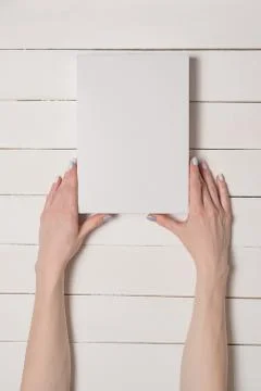 White rectangular box in female hands. Top view. White table on the backgroun 스톡 사진
