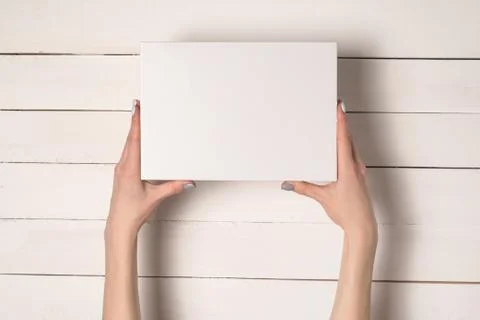 White rectangular box in female hands. Top view. White table on the backgroun 스톡 사진