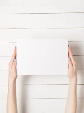 White rectangular box in female hands. Top view. White table on the backgroun Stock-Fotos