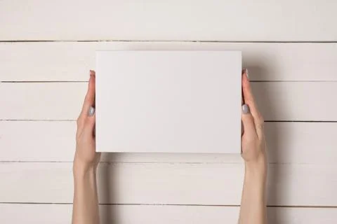 White rectangular box in female hands. Top view. White table on the backgroun Stockfoto's