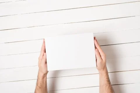 White rectangular box in male hands. Top view. White table on the background Foto stock