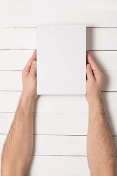 White rectangular box in male hands. Top view. White table on the background Foto stock
