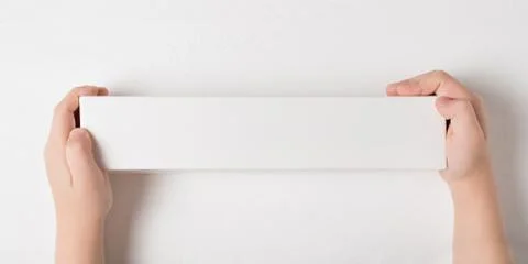 White rectangular cardboard box in children's hands. Top view, white backgrou Foto stock