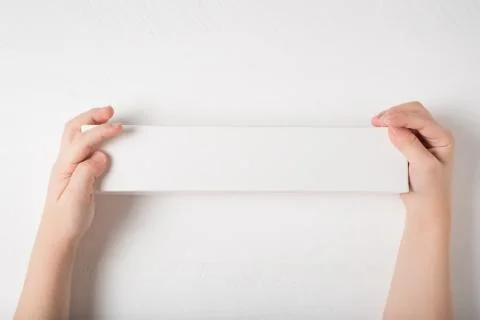 White rectangular cardboard box in children's hands. Top view, white backgrou Foto stock