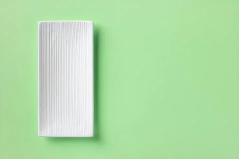 White rectangular ceramic plate over mint green textured background. Stock Photos
