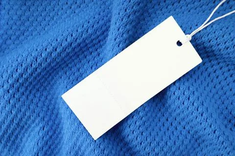 White rectangular clothing tag on blue knitted fabric background. Shopping,.. Foto stock