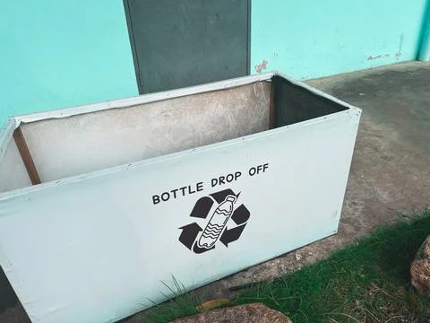 White rectangular collection bin labeled "BOTTLE DROP OFF" with recycling s.. Stock Photos