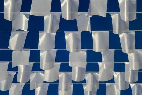 White rectangular flags hanging on ropes on background of blue sky. Stock Photos