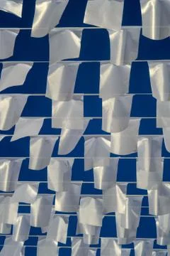 White rectangular flags hanging on ropes on background of blue sky. Stock Photos