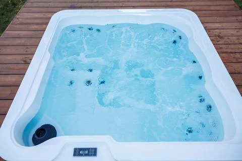 White Rectangular Hot Tub with Bubbling Water on Wooden Deck Stock Photos