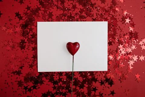 White rectangular paper with a heart in the middle on a red background with c Stock Photos