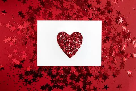 White rectangular paper with a heart in the middle on a red background with c Stock Photos