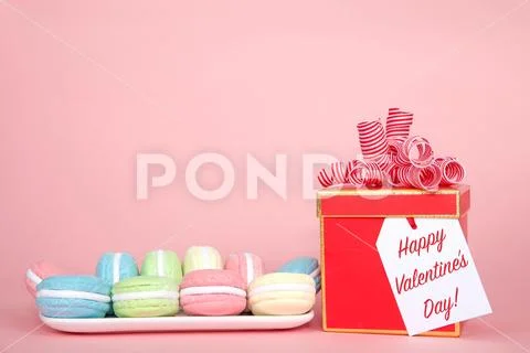 White rectangular plate with pastel colored macaron cookies laying on a pink Stock Photos
