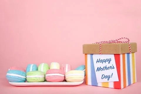 White rectangular plate with pastel colored macaron cookies laying on a pink Foto stock