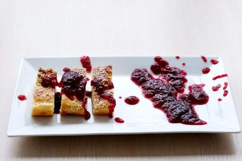 On a white rectangular plate a pie and a pie sprinkled with jam is inaccurately Stock Photos