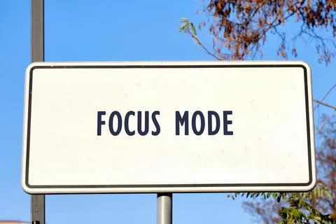 A white rectangular road sign with FOCUS MODE in bold dark letters stands aga Foto stock