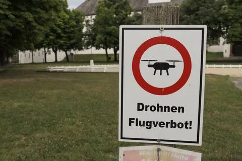 White rectangular sign with red and black text reading 'Drones flight ban' in Ge Stock Photos