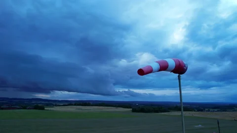 White-red airport windsock is blown by the wind against a stormy sky. Stock Footage 163852340