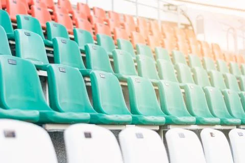 White, red and mint-colored plastic seats, arranged in rows in a stadium. Stock Photos