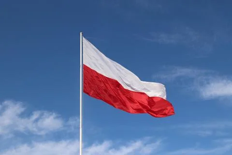 White-red horizontal flag on a flagpole developing in the wind against a blue Stock Photos