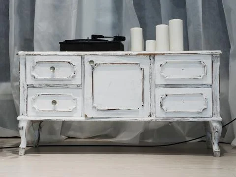 A white retro commode with a music player and candles standing on it. Interior Stock Photos