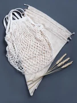 The white reusable string bags on the grey background with the wheat spikelets. Stock Photos