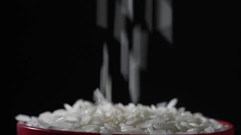 White rice falls down and fills the bowl on a black background. Slow motion Stock Footage 187662179