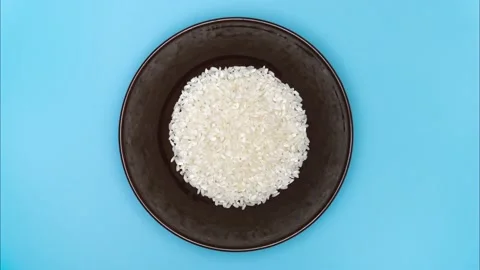 White rice fill a brown dish on a table. Top view, stop motion. Stock Footage 145483874
