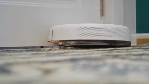 White robot vacuum cleaner bumps against a wall Stock Footage 303353904