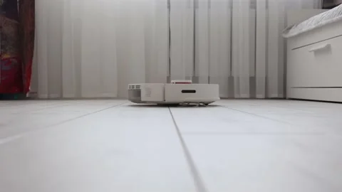 White robot vacuum cleaner effectively cleans the light laminate in the room Stock Footage 168232015