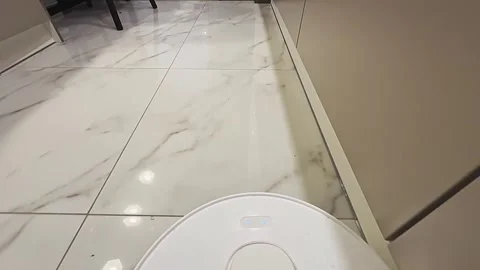 A white robot vacuum cleaner is on the floor next to a toilet Vídeo Stock 277257771