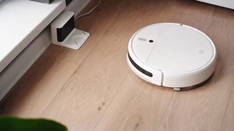 White robot vacuum cleaner leaving charging station and starting cleaning Stock Footage 303353784