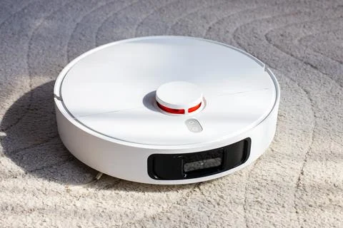 White Robot Vacuum Cleaner Operating on Grey Carpet Floor Stock Photos