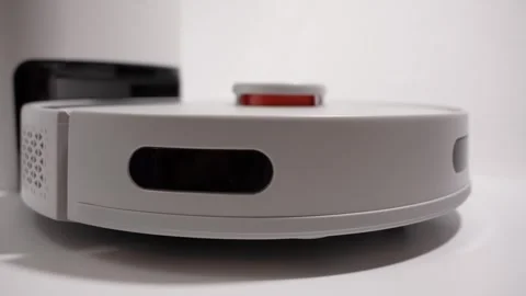 A white robot vacuum cleaner with a red button on the side Stock Footage 274967882